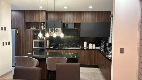a kitchen with wooden cabinets and a counter with chairs at New modern house in Qro in El Pueblito