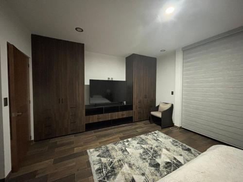 a bedroom with a bed and a tv and a chair at New modern house in Qro in El Pueblito