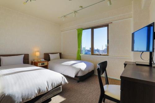 a hotel room with two beds and a flat screen tv at Hotel New Saitama in Saitama