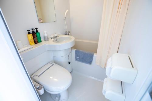 a white bathroom with a toilet and a sink at Hotel New Saitama in Saitama