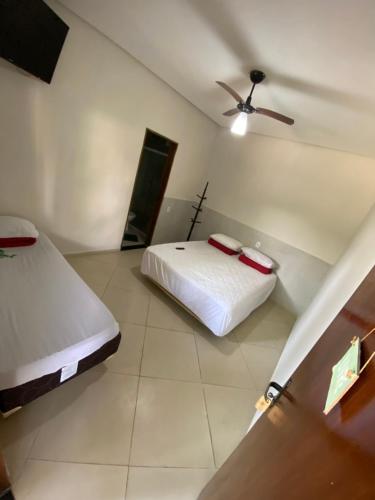 a bedroom with two beds and a ceiling fan at Pousada Tropical in Aparecida