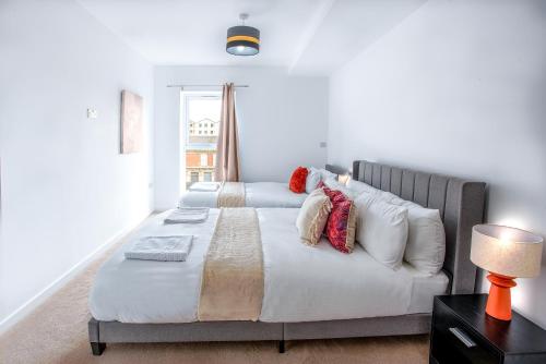 a bedroom with two beds and a table with a lamp at Modern Downtown Gem- Brand New Apartments on Cannon St in Preston
