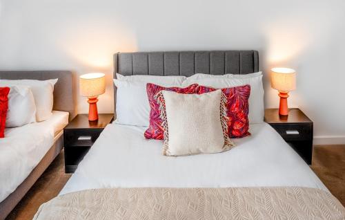 a bedroom with a bed with red pillows and two lamps at Modern Downtown Gem- Brand New Apartments on Cannon St in Preston