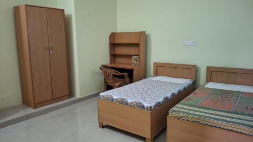 a bedroom with two beds and a desk with a desk at Riddhi Homestay in Dahmi