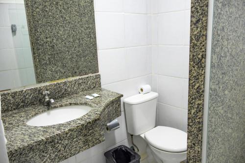a bathroom with a toilet and a sink and a mirror at Bahia Sol e Mar in Salvador