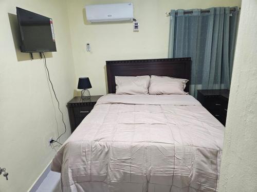 a bedroom with a bed with a tv on the wall at Eastern Breeze in Hainamosa