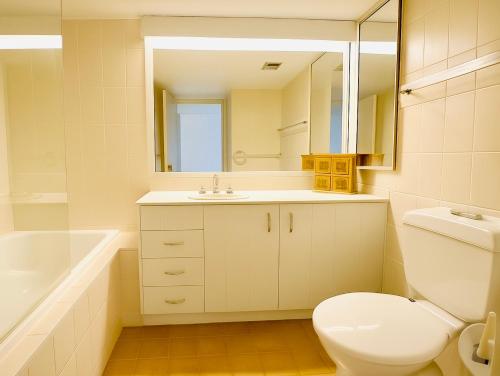 a bathroom with a toilet and a sink and a mirror at 2Br Apartment, Pool, 12 mins to Airport in Bilambil Heights