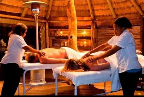 Dos mujeres en una sala de masajes con una persona acostada en las camas. en Princess Spa & Lodge, en Pretoria