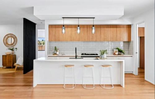 a kitchen with a white counter and bar stools at Stylish Modern Getaway Geelong in Geelong