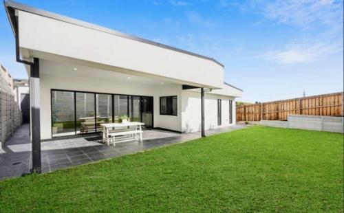 a white house with a green lawn in front of it at Stylish Modern Getaway Geelong in Geelong