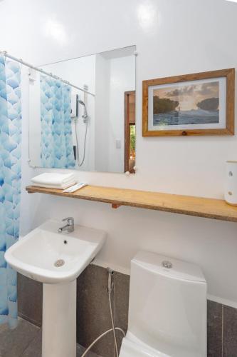 a bathroom with a sink and a toilet and a mirror at Fat Lips Surf Lodge in General Luna