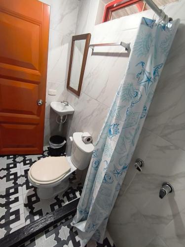 a bathroom with a toilet and a shower curtain at Finca Tradicional La Rochela in Montenegro