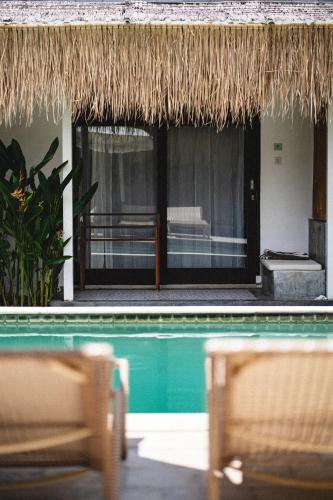 a resort with a swimming pool and a straw roof at Suku Lifestyle Hotel & Villas in Selong Belanak