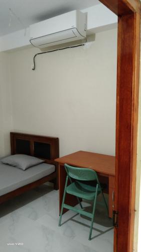 a bedroom with a desk and a bed and a green chair at River way in Ratnapura