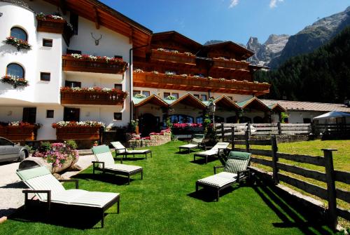 un bâtiment avec des chaises sur l'herbe devant lui dans l'établissement Hotel Stalon Alpine Chic, à San Martino di Castrozza