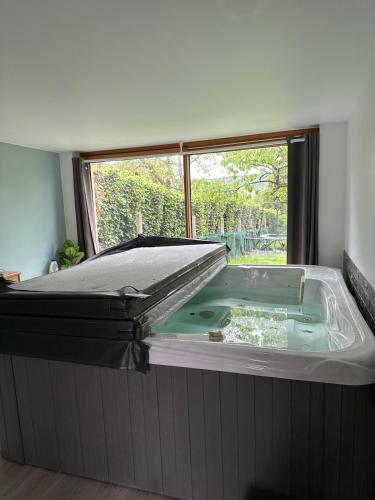 a hot tub in a room with a window at Chambre pour 4 personnes avec SdB privative et jacuzzi in Le Petit-Couronne