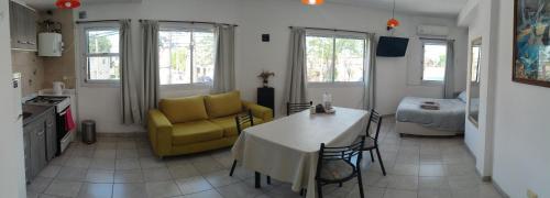 cocina y sala de estar con mesa y silla amarilla en Depto Cogli, en Ezeiza