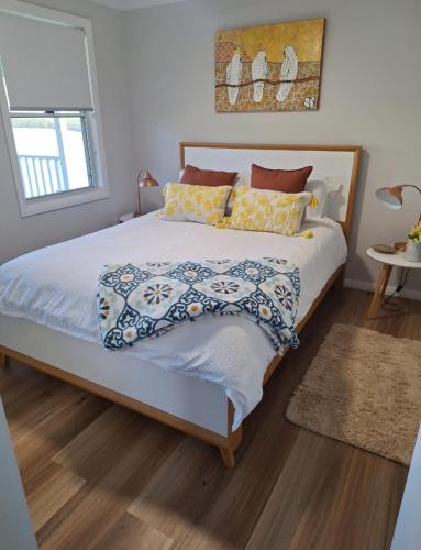 a bedroom with a large bed with pillows at The Cottage in Moruya