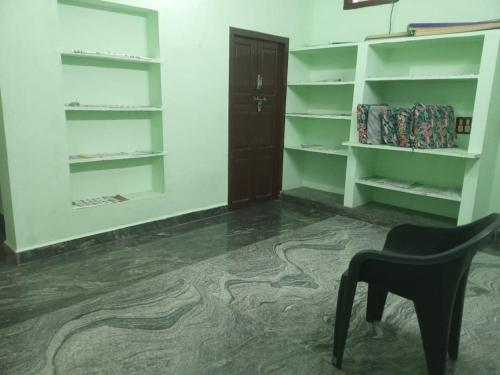 Near by Annamalaiyar temple 2 Home stay في تيروفانمالي: غرفة بها رفوف بيضاء وكرسي وباب
