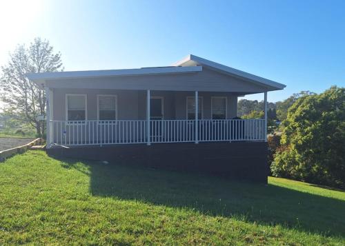 ein kleines Haus mit einer Veranda auf einem Rasen in der Unterkunft The Cottage in Moruya