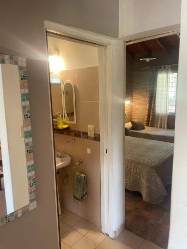 un bagno con un lavandino, un letto e uno specchio di Cabañas Canluma a Villa Giardino