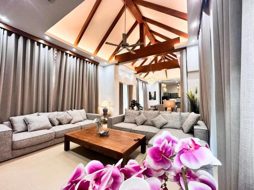 a living room with couches and a table and flowers at La Nissta Villa 4bdr pool Villa Phuket in Koh Lone