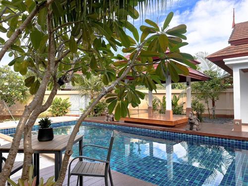 a swimming pool with a table and chairs next to a building at La Nissta Villa 4bdr pool Villa Phuket in Koh Lone