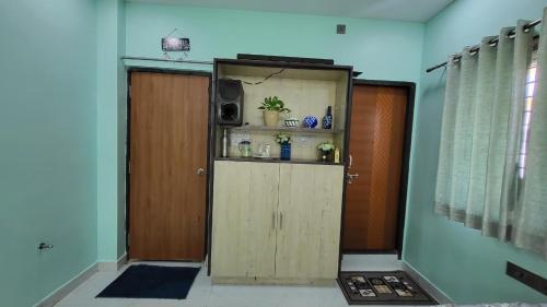 a room with a door and a cabinet with a television at Private room in a residential area in Hospet