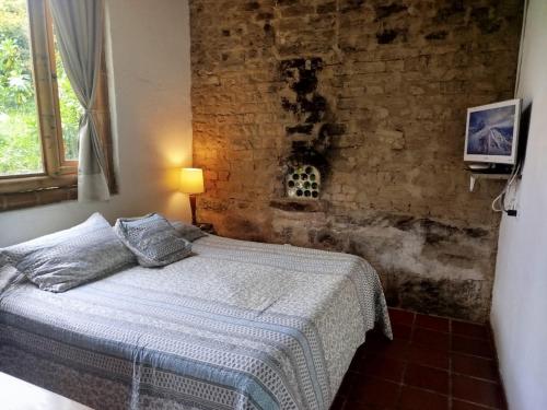 a bedroom with a bed and a brick wall at HOSTAL CASA DE GUADUA/ THE BAMBOO HOUSE in Choachí