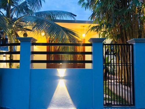 a blue gate with a fence and a palm tree at Hiriketiya Green Haven Villa in Dickwella