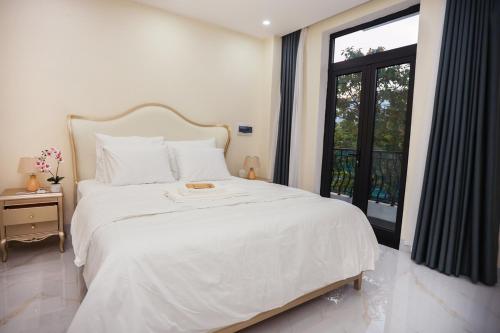 ein Schlafzimmer mit einem großen weißen Bett mit einem Fenster in der Unterkunft M&M homestay in Quang Tri