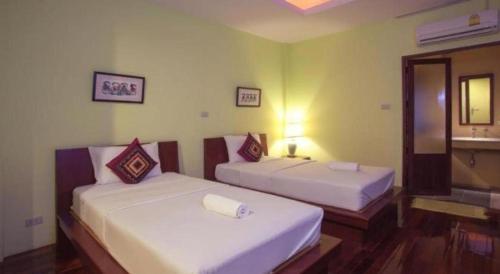 two beds in a hotel room with a mirror at Baan Lapoon Hotel in Lamphun