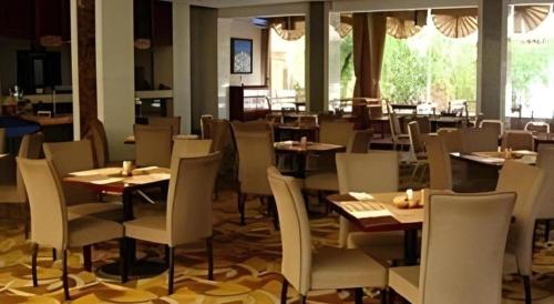 a dining room with tables and chairs in a restaurant at Lijiang Conifer Lishui Yangguang Hotel in Lijiang