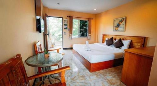 a bedroom with a bed and a table in it at Phoem Phoon 2 Hotel in Nan