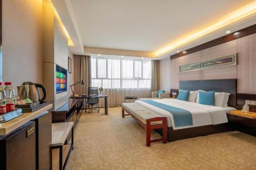 a hotel room with a large bed and a desk at Aksu Pudong Holiday Hotel in Aksu