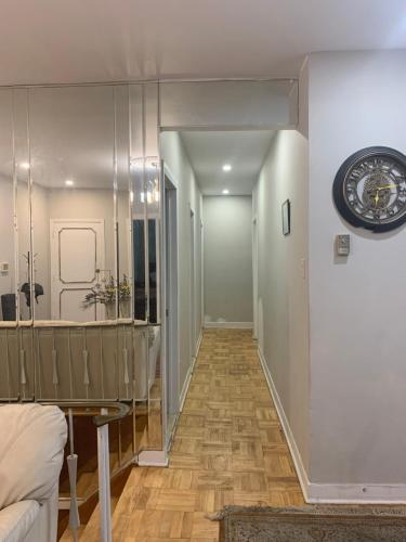 a living room with a clock on the wall and a hallway at Montreal Accommodation Steps Downtown 17mins airport in Montréal