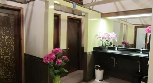 a bathroom with a sink and a vase of pink flowers at Chodkamol Place 57 in Nakhon Si Thammarat