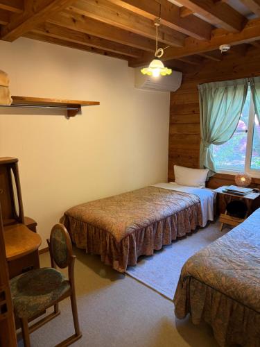 a bedroom with two beds and a chair and a window at Sanrinsha in Takamori