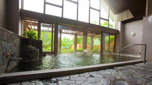 a large pool of water in a building with windows at Takato Sakura Hotel in Ina