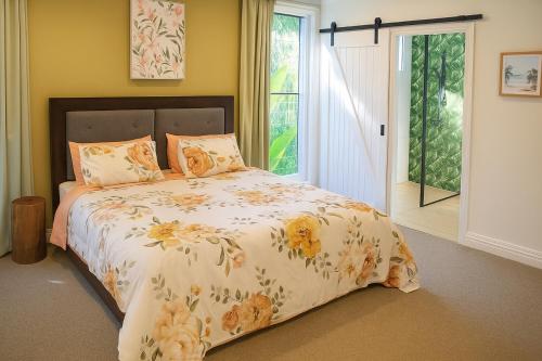 Weyba DownsにあるStunning Modern Queenslander, steps to Lakeのベッドルーム1室(花柄の掛け布団付きのベッド1台付)