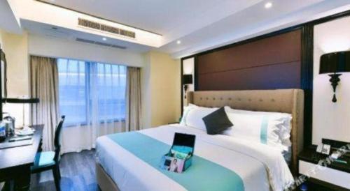 a bedroom with a bed with a desk and a laptop on it at Xana Hotelle Neijiang City Center Branch in Neijiang