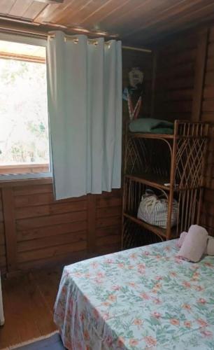 a bedroom with a bed and a window with a curtain at Brayan`s House in Ilha do Mel