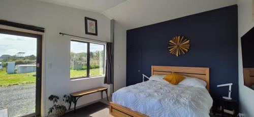 a bedroom with a bed with a blue wall at Valley Views Near City & Coast in Tahere