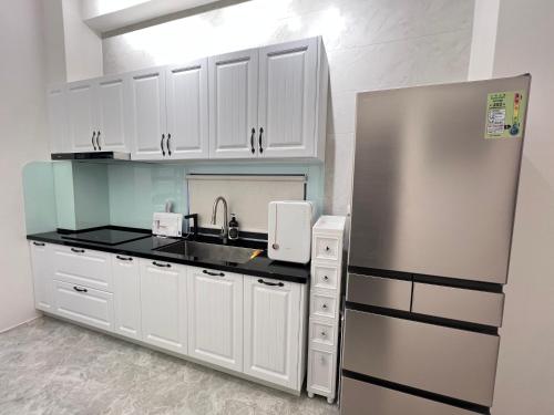 Una cocina con gabinetes blancos y un refrigerador de acero inoxidable. en Tiansheng Anjia B&B, en Taitung