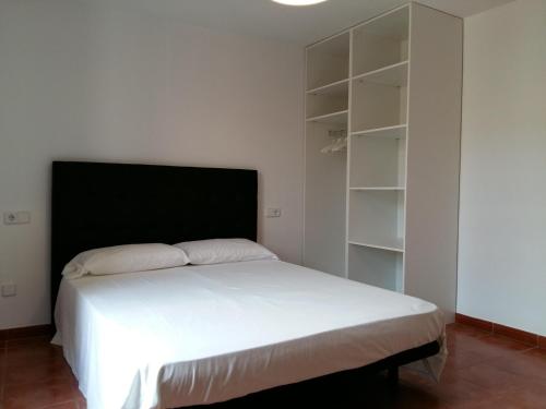 a bedroom with a large white bed and shelves at Can Mayol in Alaró