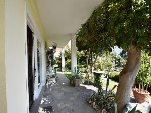 a porch with a tree and a table and chairs at Chalet by Lake Maggiore with Garden Views in Verbania