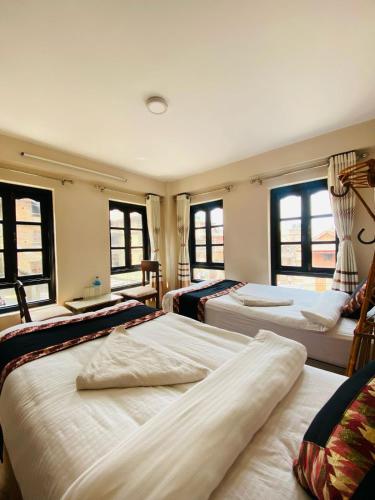 a room with three beds in a room with windows at Hotel Durbar Side in Bhaktapur