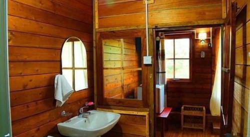 a wooden bathroom with a sink and a mirror at Ma-Oya Retreat in Andiramada