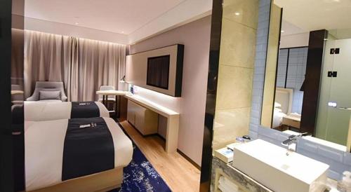 una camera d'albergo con un letto e un lavandino di Echarm Hotel Kunming High-speed Railway South Station Chunrong Street Metro Station a Kunming