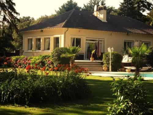 a house with a garden with flowers in front of it at Villa La Clef Des Champs in Chailly-en-Bière